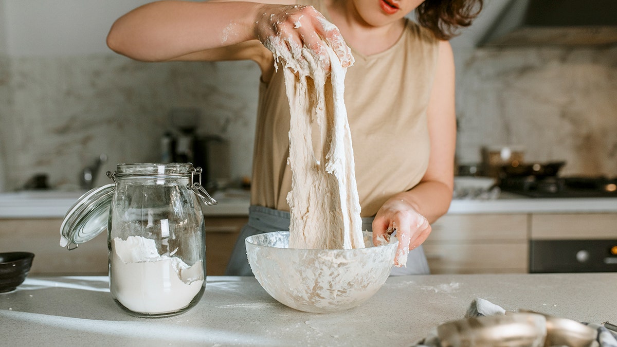 A woman makes sourdough bread in a home kitchen.
