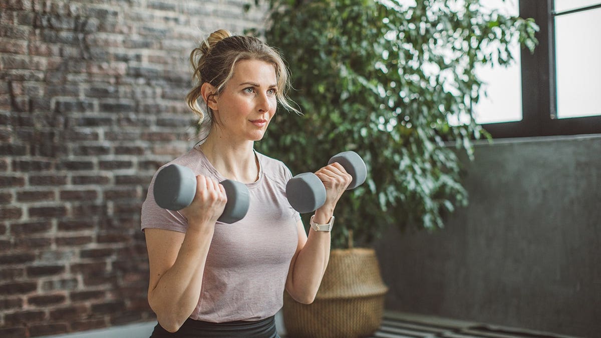 Women exercise with weights at home during pandemic isolation.