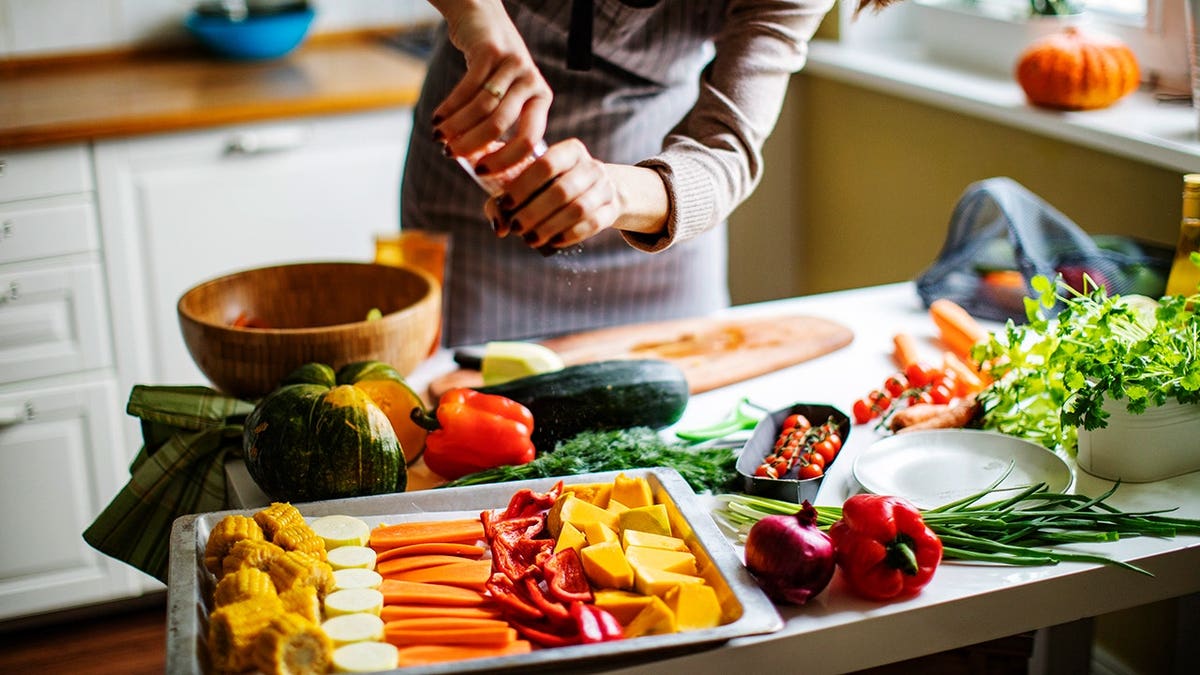 Young adult woman cooks vegan food in a kitchen.