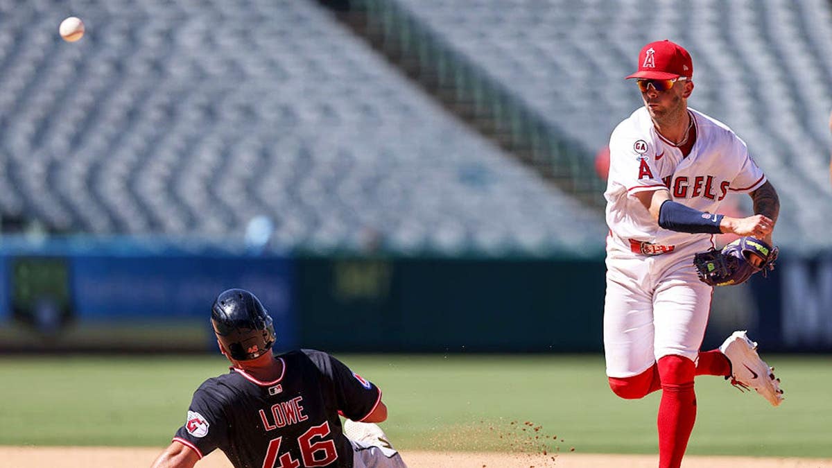 Zach Neto #9 of the Los Angeles Angels turns a double play over Nathaniel Lowe #46 of the Cleveland Guardians.