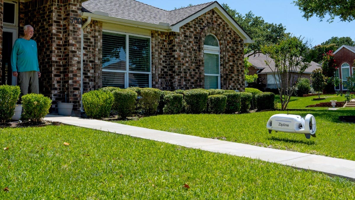 A delivery drone is lowered onto a patient's lawn.