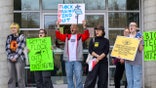 protesters hold signs demonstrating against roadside license plate cameras