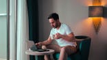 A man on a computer in a hotel
