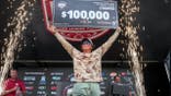man holds up a giant check for $100,000