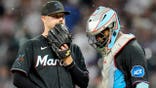 Janson Junk speaks with catcher Brian Navarreto during a baseball game.