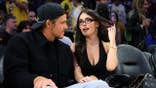 Justin Herbert and Madison Beer seated together at a basketball game.