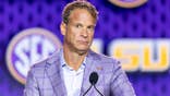 Lane Kiffin speaks at a podium during SEC Football Kickoff Media Day.
