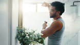 A man sprays deodorant under his arm.