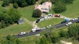 An aerial view of a house with cars parked in front