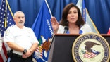 Jeanine Pirro speaks at a microphone to the press.