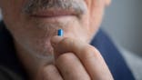 Senior man holds a pill in close-up.