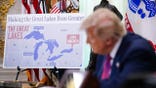 President Donald Trump signs an executive order as a map labeled Lake America is displayed.