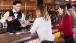 Portrait of barman and people who are standing near bar counter in luxurious restaurant