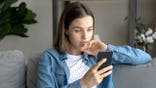 Serious Young Woman Scrolls on Smartphone