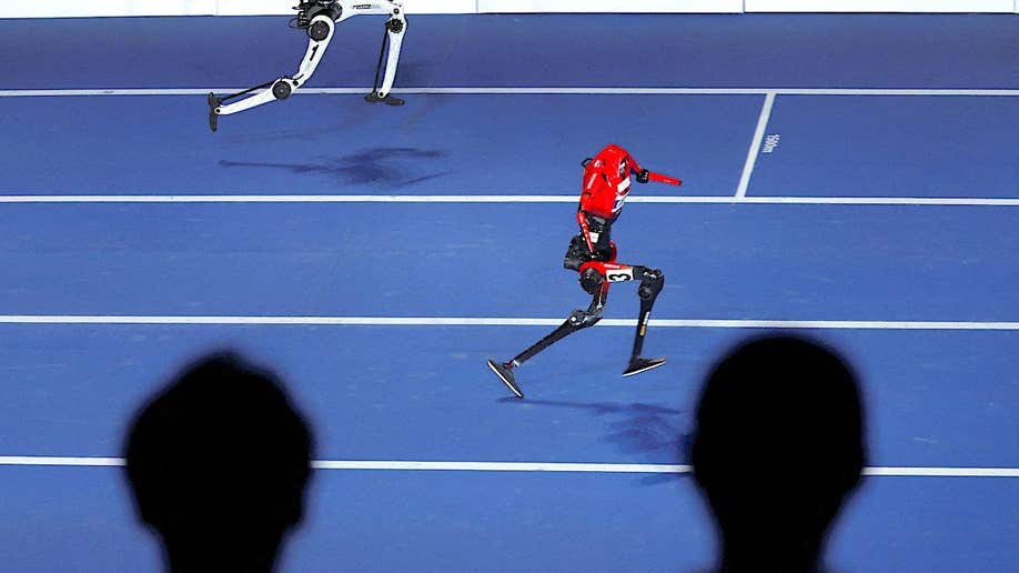 Spectators watch as a Lightning humanoid robot by Honor and a Tiangong Ultra humanoid robot compete in a 100-meter exhibition race during the opening ceremony for the second World Humanoid Robot Games at the National Speed Skating Oval in Beijing, China, on Aug. 22, 2026.