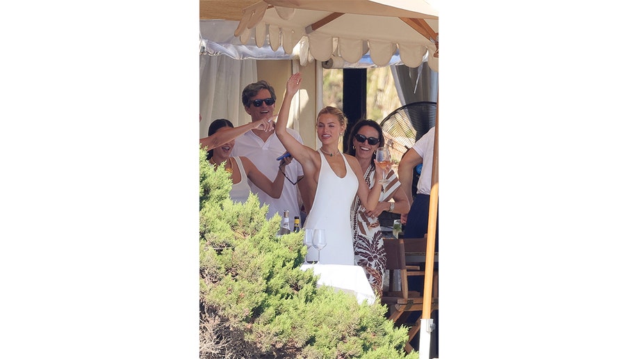 Brooks Nader raises an arm while holding a drink at an outdoor restaurant.