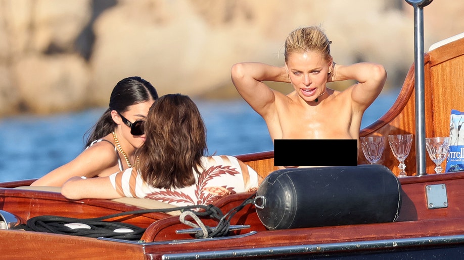 Brooks Nader climbs a boat ladder from the water as a woman looks on.