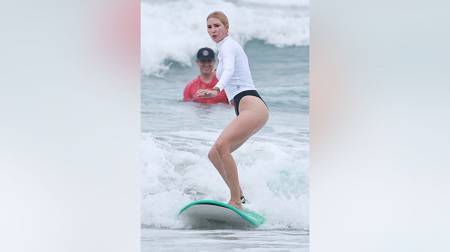 Ivanka Trump surfing in Costa Rica in a white long sleeve and black bottoms in August 2026.