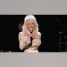 Dolly Parton smiling while singing on stage.