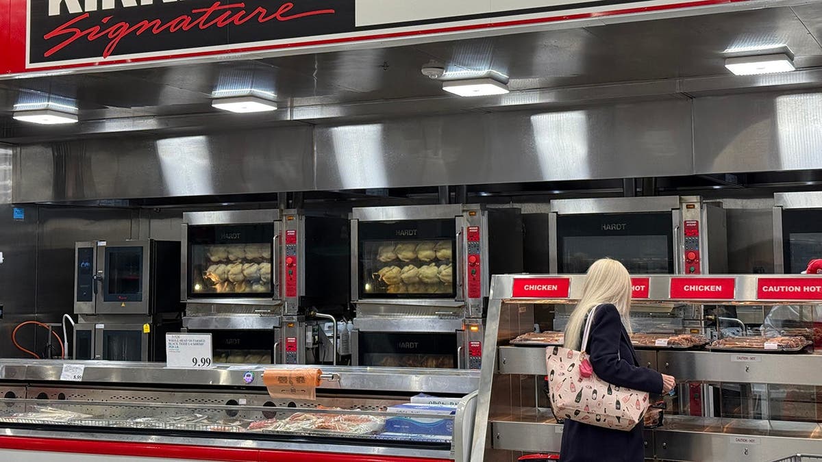 Customer selecting rotisserie chicken at Costco store.