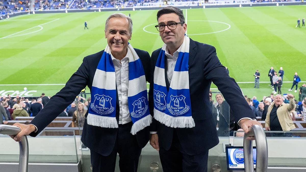Mark Carney and Andy Burnham standing together at an Everton football match
