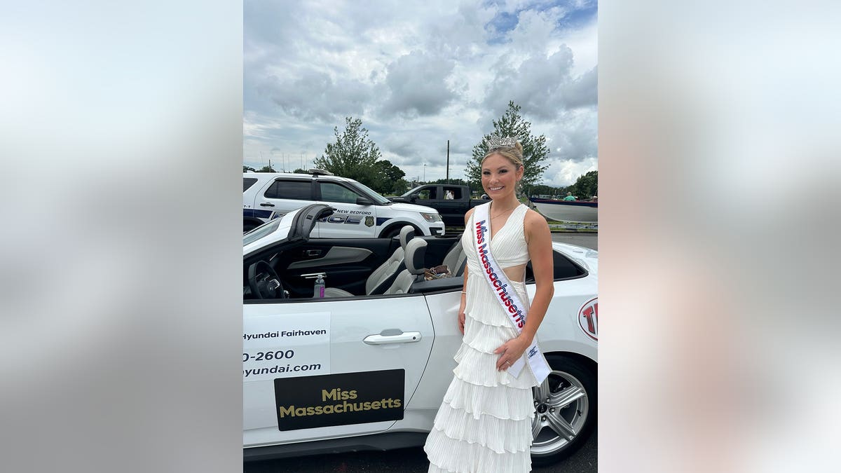 Ashlyn Mercier wearing a sparkling gown in front of a police car.