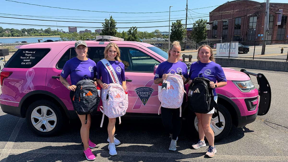 Ashlyn Mercier surrounded by women in front of a pink car.