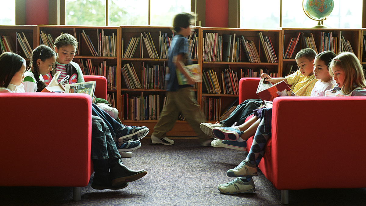 Students read books together in a school classroom.