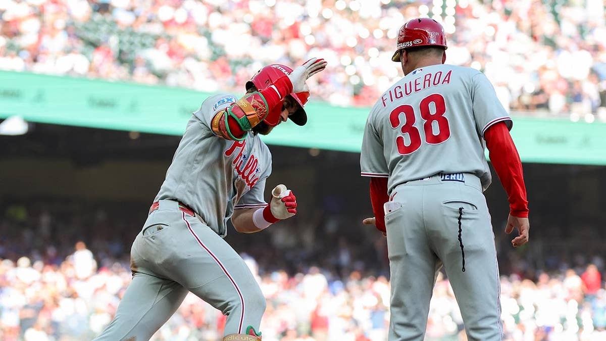 Bryce Harper celebrates with first-base coach Paco Figueroa