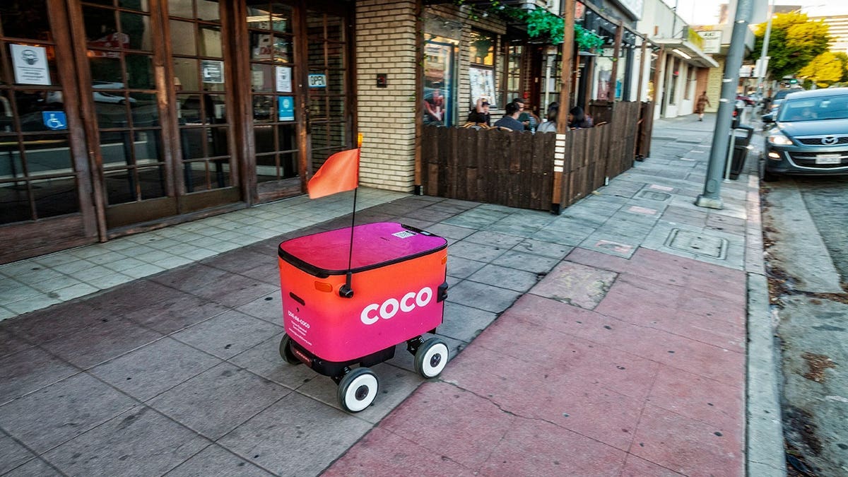 Coco delivery bot driving down the sidewalk.