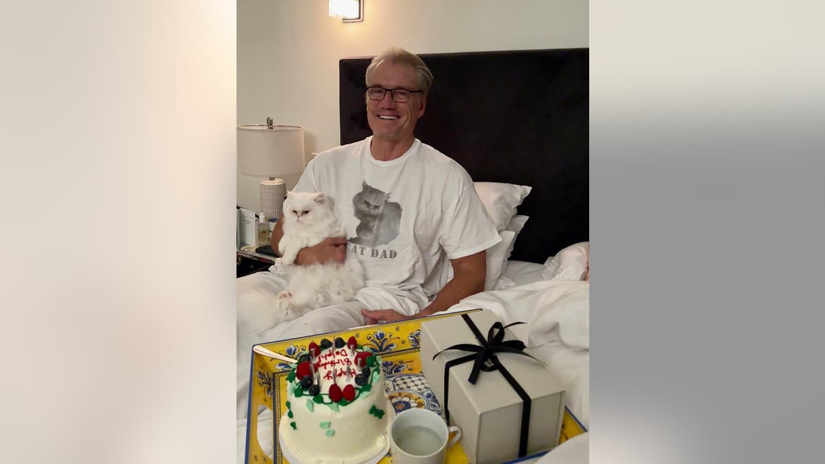 Dolph Lundgren sitting in bed with his cat.