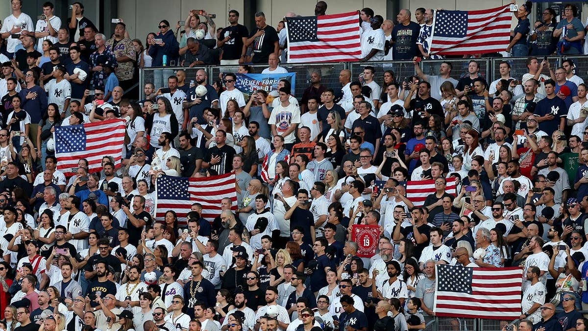 Fans holding American flags and signs at Yankee Stadium