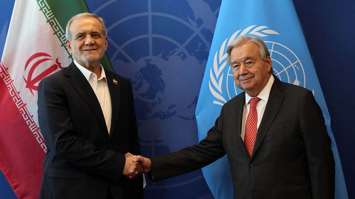 Iranian President Masoud Pezeshkian (L) shakes hands with the United Nations (UN) Secretary General Antonio Guterres