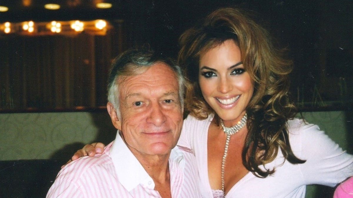Hugh Hefner smiling and embracing Sandra Taylor for a photo.