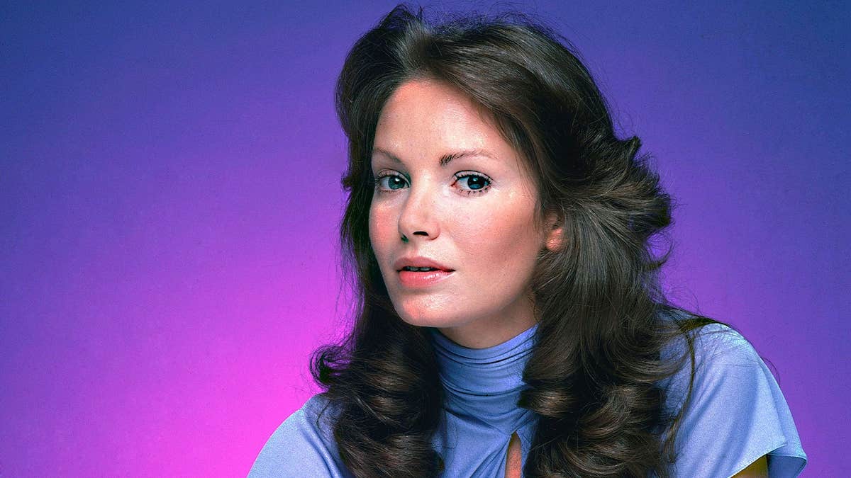 Jaclyn Smith posing as a model in a light blue top.