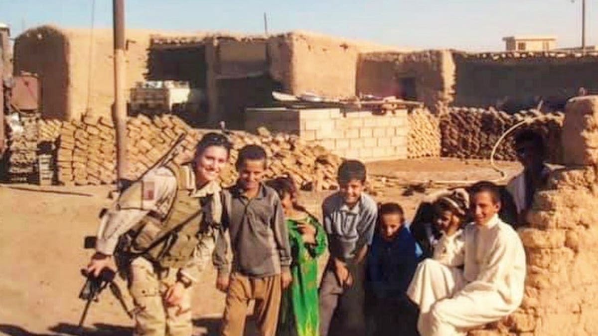 Lindsey Schmidt in Army wear with Iraqi children outside in Iraq.