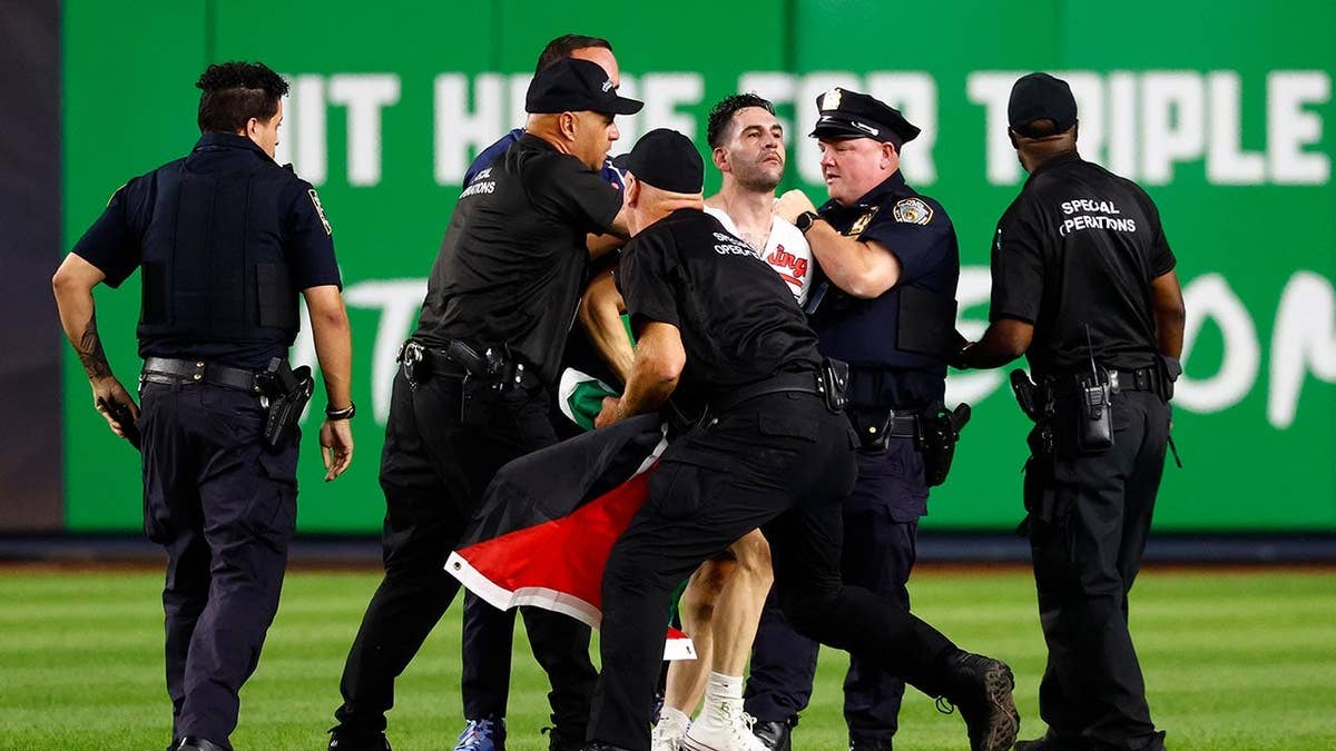 Police detain an unidentified man on the field at Yankee Stadium