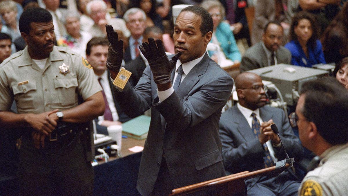 O.J. Simpson examines a pair of gloves in court during his murder trial.