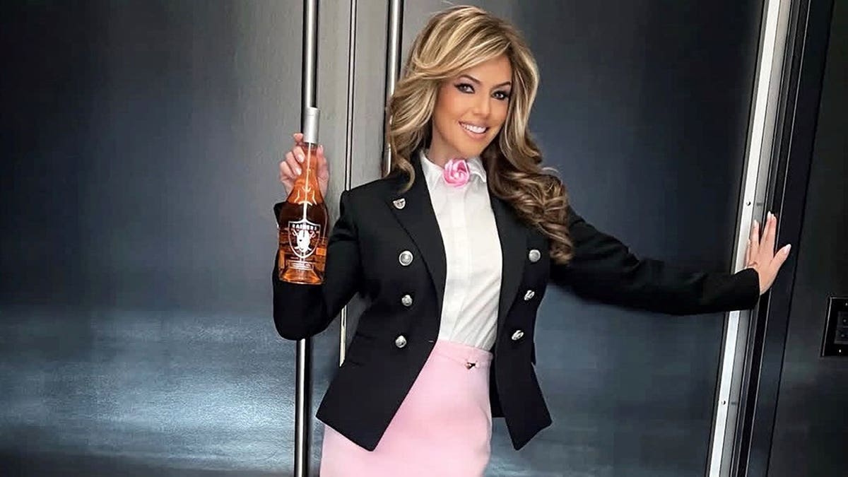 Sandra Taylor smiling and holding a bottle of rose.