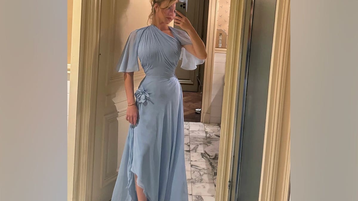 Sydney Sweeney takes a mirror selfie while wearing a flowing light blue gown with a cinched waist.