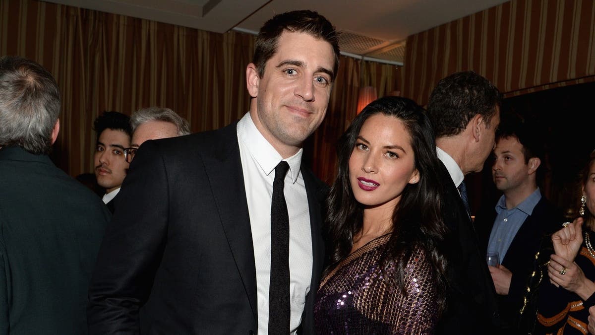 Aaron Rodgers and Olivia Munn stand together at a cocktail reception in West Hollywood.