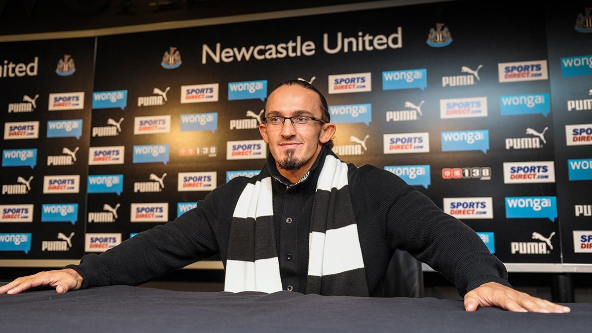 Adrian Neville sits in front of advertising boards in a media suite at St. James' Park.