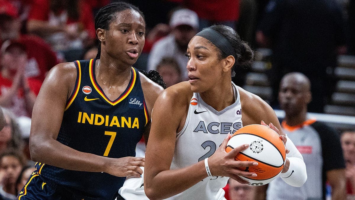 A'ja Wilson holds the ball while Aliyah Boston defends during a WNBA Playoffs game.