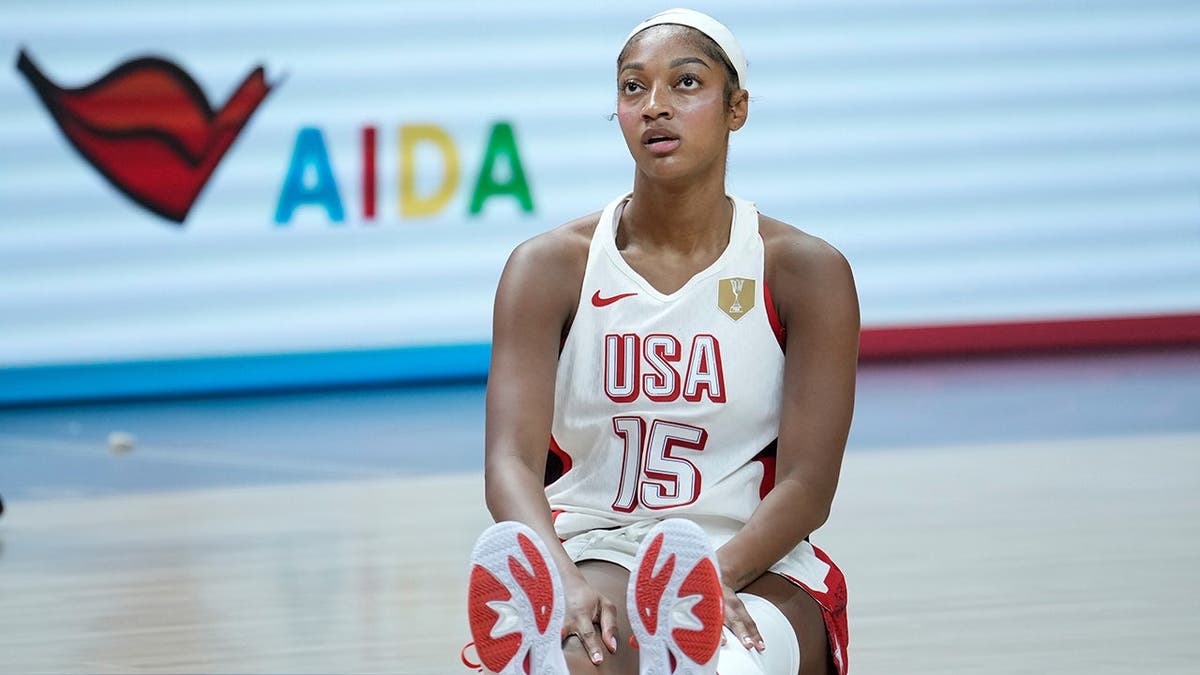 Angel Reese sits on the court during a Women's Basketball World Cup match.