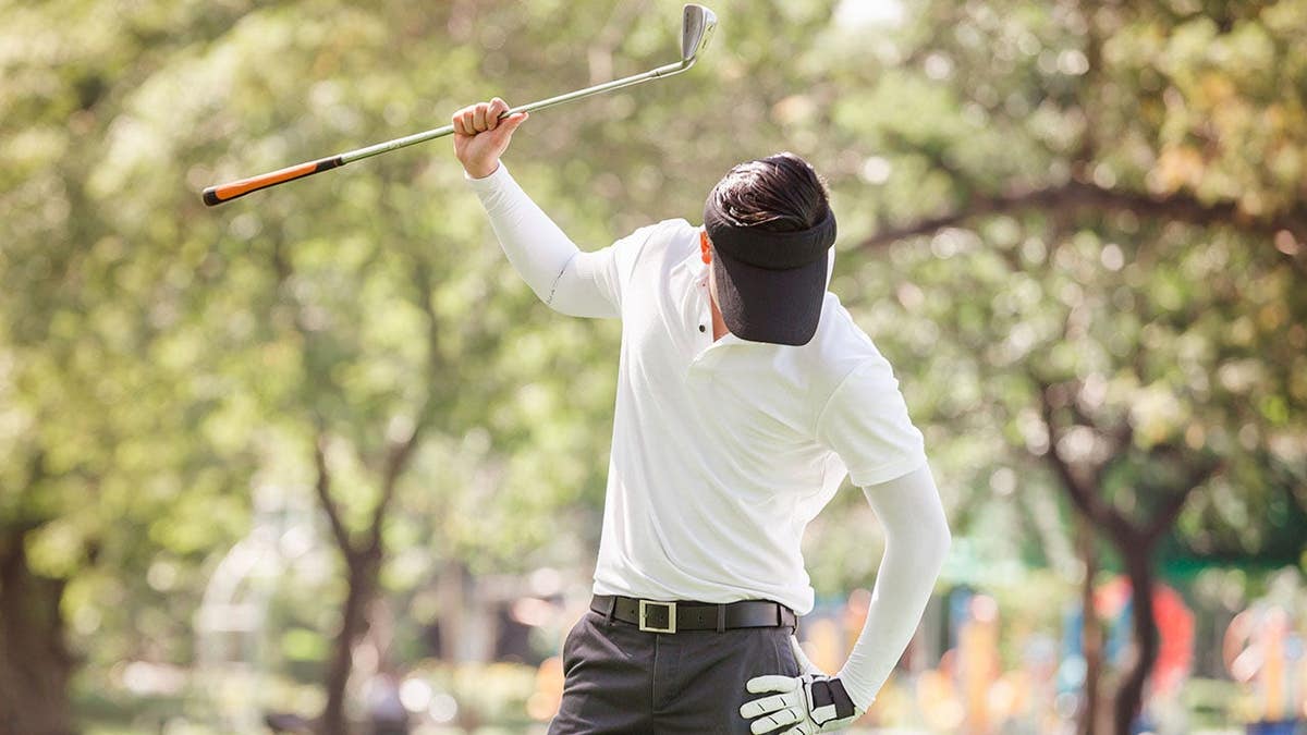 An angry golfer attempts to break his golf club.