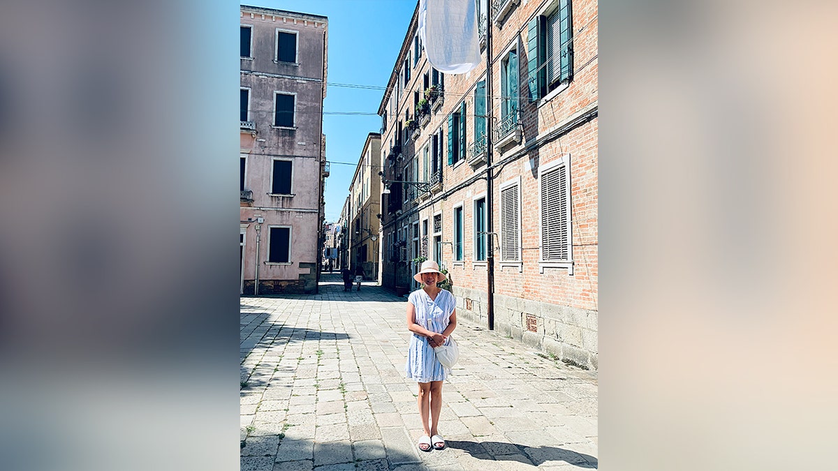 Woman stands on cobblestone street