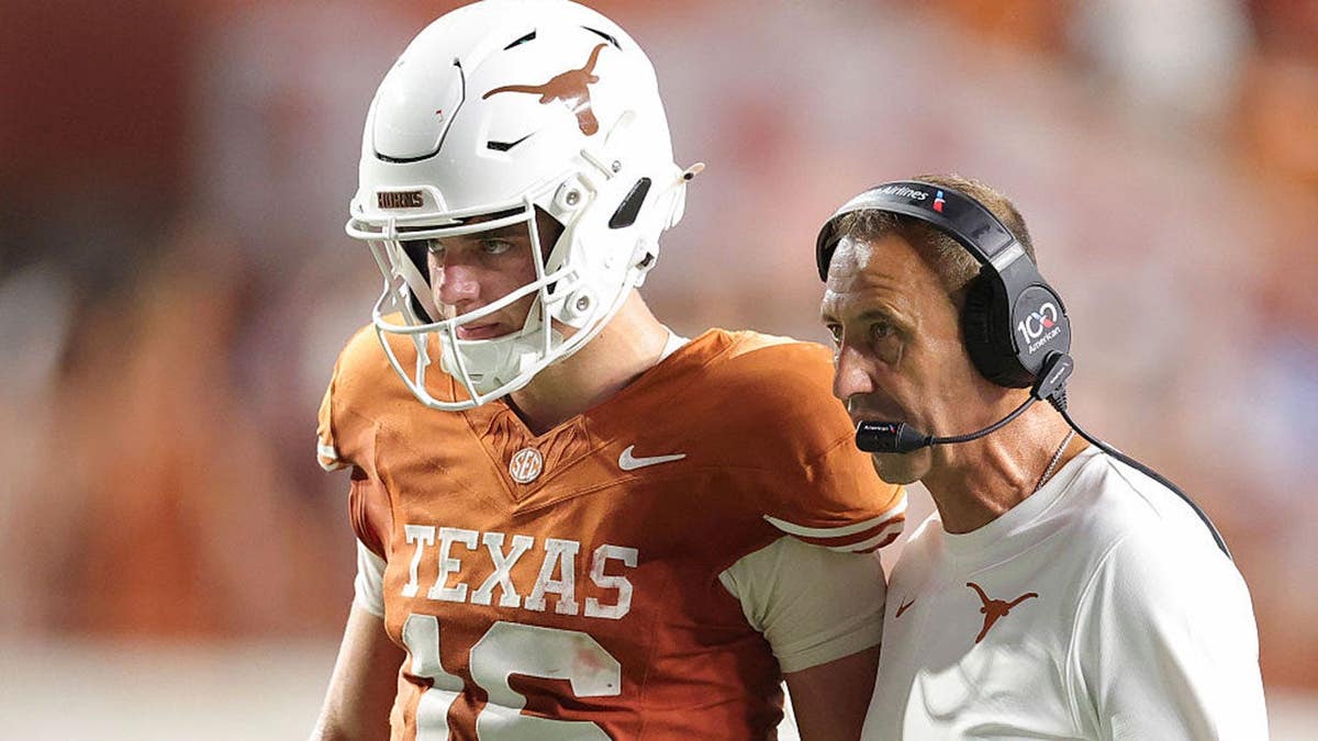 Arch Manning #16 speaks with head coach Steve Sarkisian during a Texas Longhorns game.