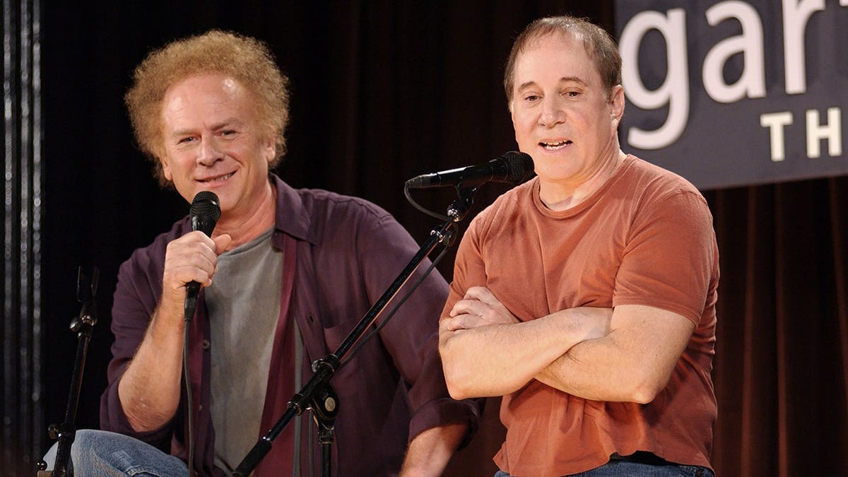Art Garfunkel and Paul Simon speak onstage during a press conference.
