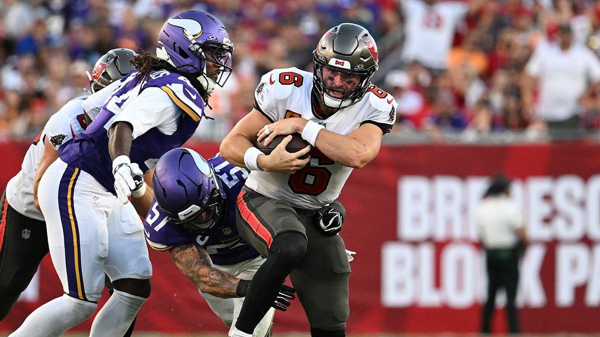 Baker Mayfield is tackled by Joshua Metellus and Blake Cashman during an NFL game.