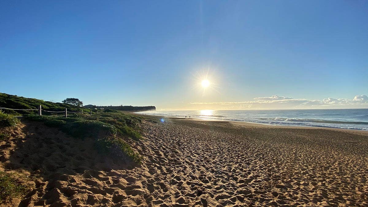 Beach at sunrise with sun near horizon.